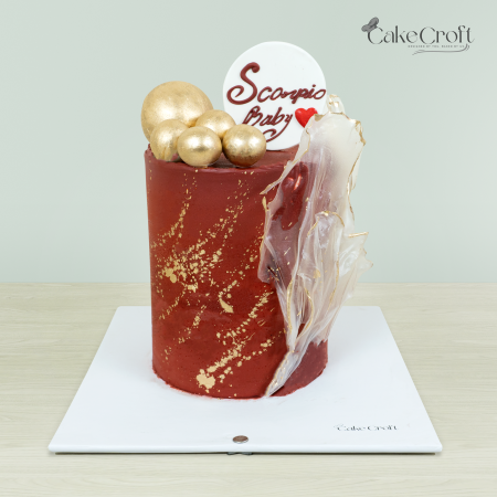 Scorpio-themed cake with deep red base, gold splatters, and sugar sculptural accents by Cakecroft.