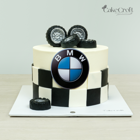 BMW-themed cake with black and white checkered fondant, BMW logo, and edible car tires by Cakecroft.