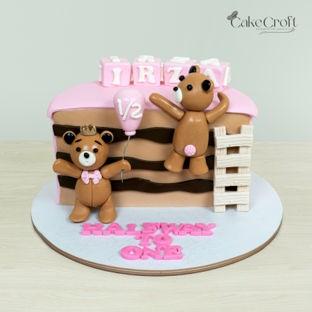 Halfway to One teddy bear-themed cake with two teddy bears, pink and brown accents, and a '1/2' balloon topper by Cakecroft.