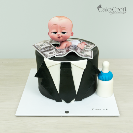 Baby Boss-themed cake with a Baby Boss figurine, dollar bills, black tuxedo design, and a blue baby bottle by Cakecroft.