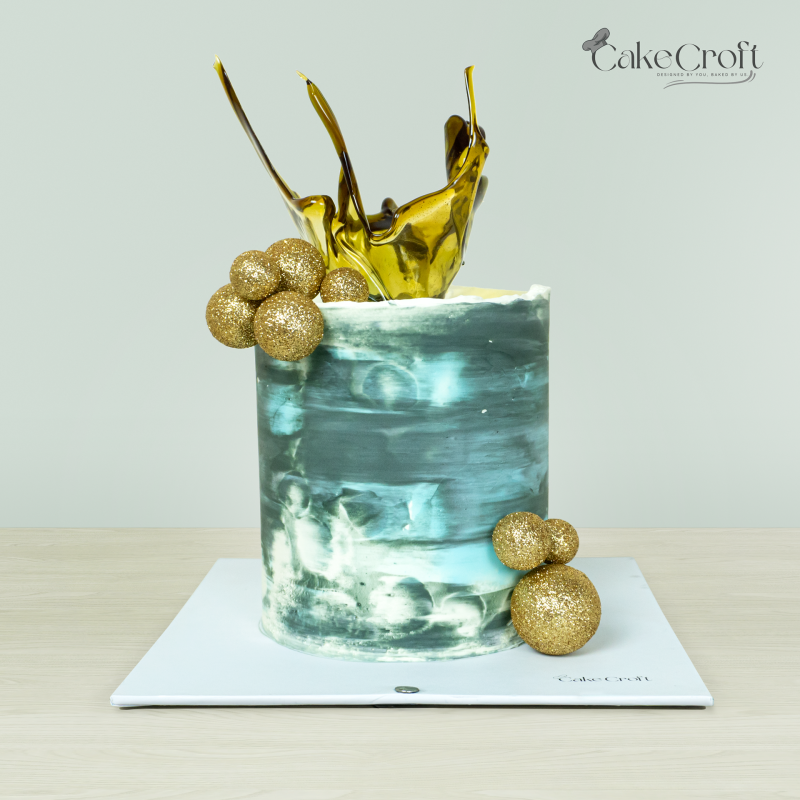 Abstract-themed cake with blue and grey brushstrokes, golden sugar shards, and glittering gold spheres by Cakecroft