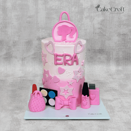 A pink and white fondant cake decorated with hearts, stars, a bow, and makeup-inspired toppers, personalized with the name 'Era.'