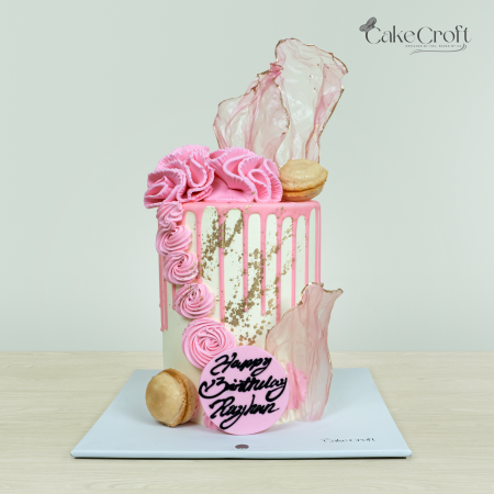 Pink and white birthday cake with buttercream ruffles, macarons, and a drip design, by Cakecroft