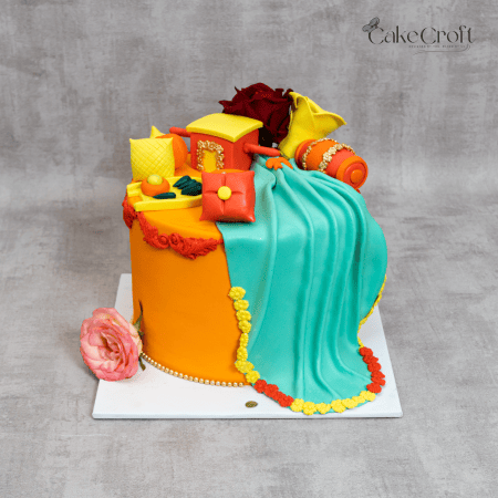 Vibrant orange and turquoise cake with traditional Indian decor accents, perfect for festive occasions.