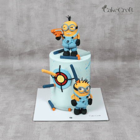 A Minion-themed cake with fondant Minion characters, a colorful target design, and Nerf-inspired darts, perfect for kids' celebrations