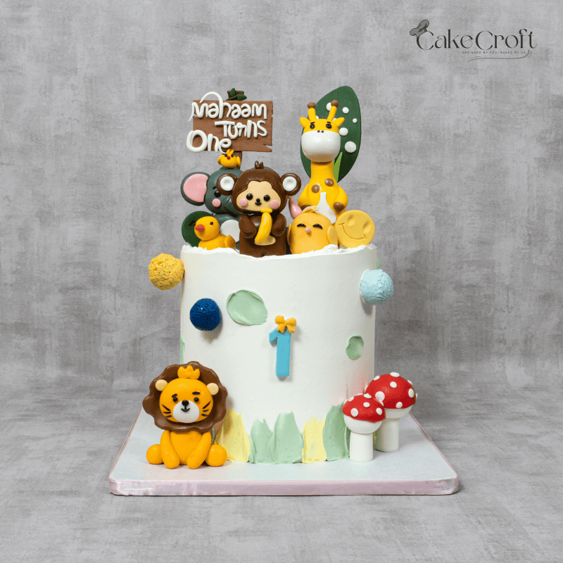 A jungle-themed birthday cake with fondant animals, including a lion, giraffe, and monkey, decorated with mushrooms and playful accents.