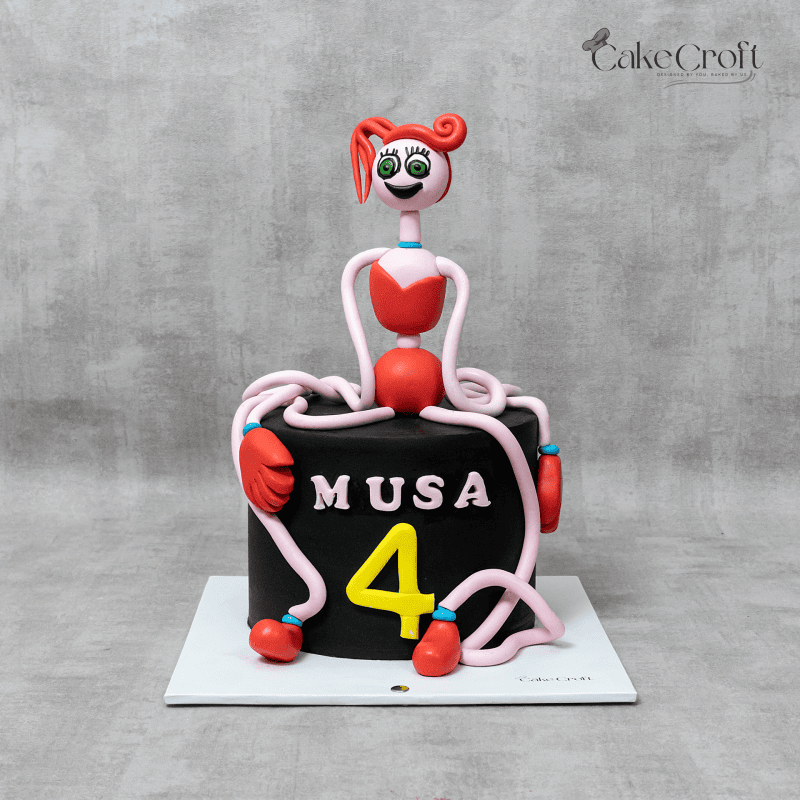 A playful black and pink themed cake featuring a vibrant figure inspired by Poppy Playtime, with colorful accents and the name "MUSA" along with the number 4.