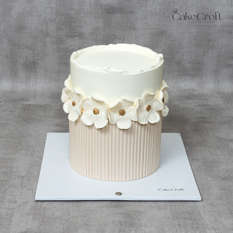 Minimalist ivory and beige floral cake with white textured flowers and gold centers