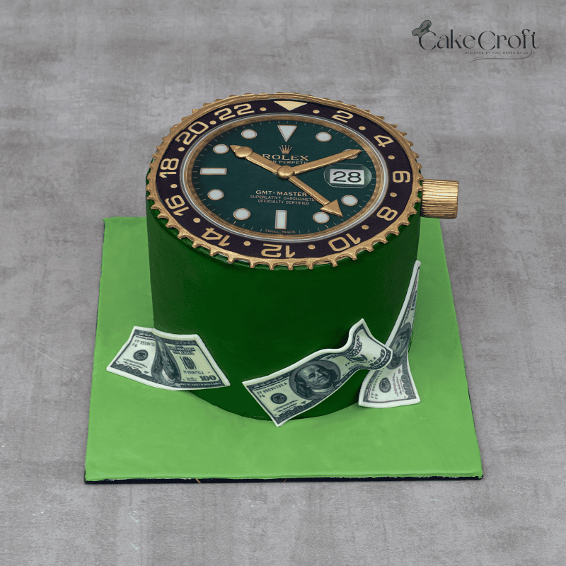 A green fondant cake topped with a realistic Rolex watch face, gold detailing, and edible money decorations on the sides.