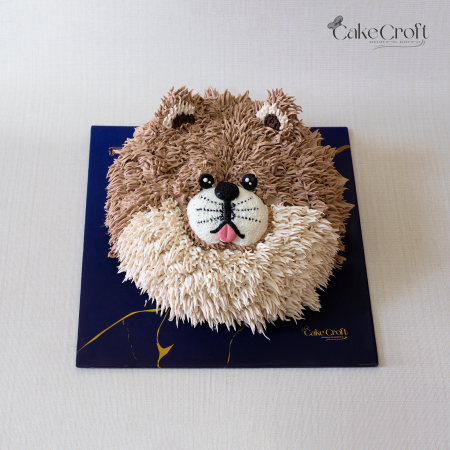 Dog-themed cake designed as a fluffy brown and cream dog face with buttercream fur details and a cute snout.
