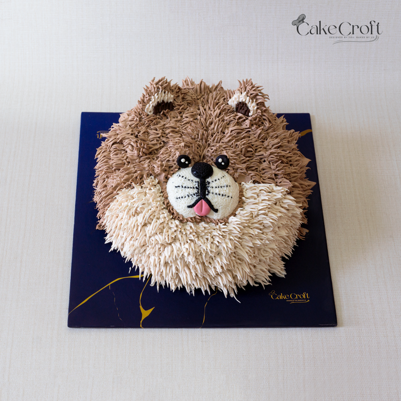 Dog-themed cake designed as a fluffy brown and cream dog face with buttercream fur details and a cute snout.
