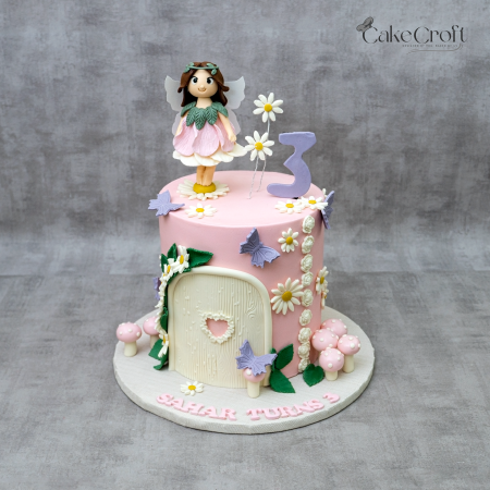 Fairy garden themed fondant cake with pink base, fairy topper, flowers, butterflies, and mushrooms by CakeCroft Dhaka.