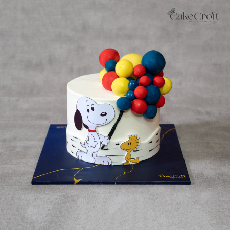 Snoopy and Woodstock themed birthday cake with ivory white base, colorful 3D balloons, and cartoon artwork by CakeCroft Dhaka.