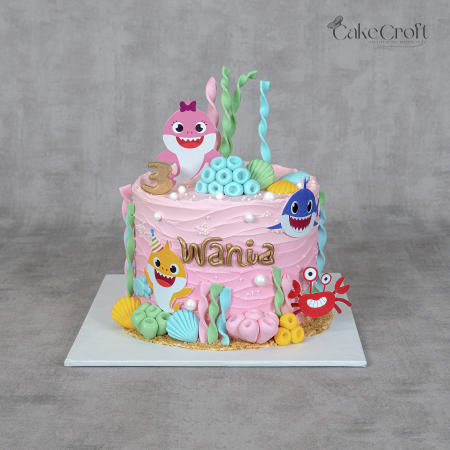 Baby Shark theme pink birthday cake with colorful sea decorations, fondant shells, and Baby Shark family toppers by CakeCroft Dhaka.