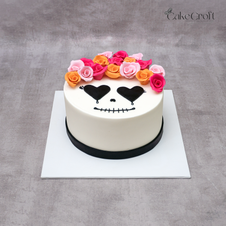 Day of the Dead cake with fondant skull face, black heart eyes, and colorful rose crown in pink, orange, and peach by CakeCroft Dhaka.