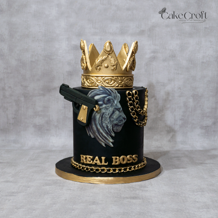 Luxury black and gold “Real Boss” fondant cake with gold crown topper, lion artwork, and metallic chain decorations by CakeCroft Dhaka.