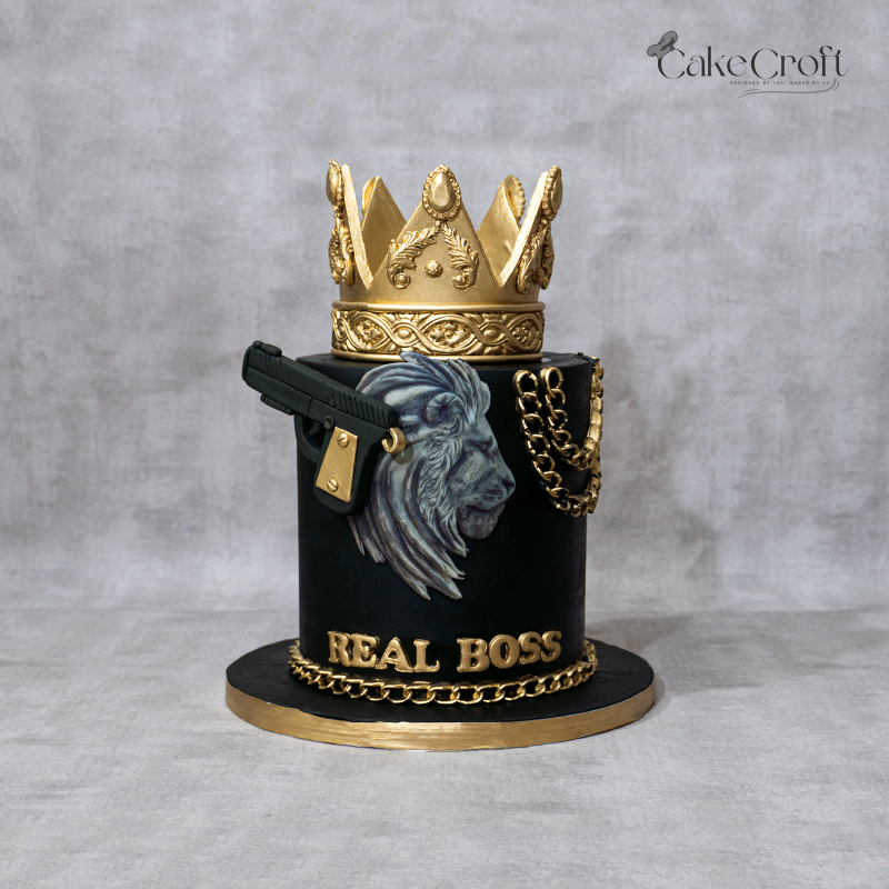 Luxury black and gold “Real Boss” fondant cake with gold crown topper, lion artwork, and metallic chain decorations by CakeCroft Dhaka.