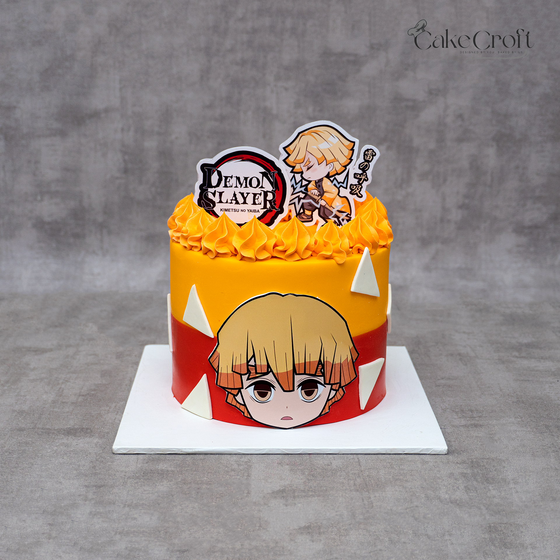 Demon Slayer Zenitsu themed birthday cake with yellow-orange frosting, anime toppers, and geometric decorations.