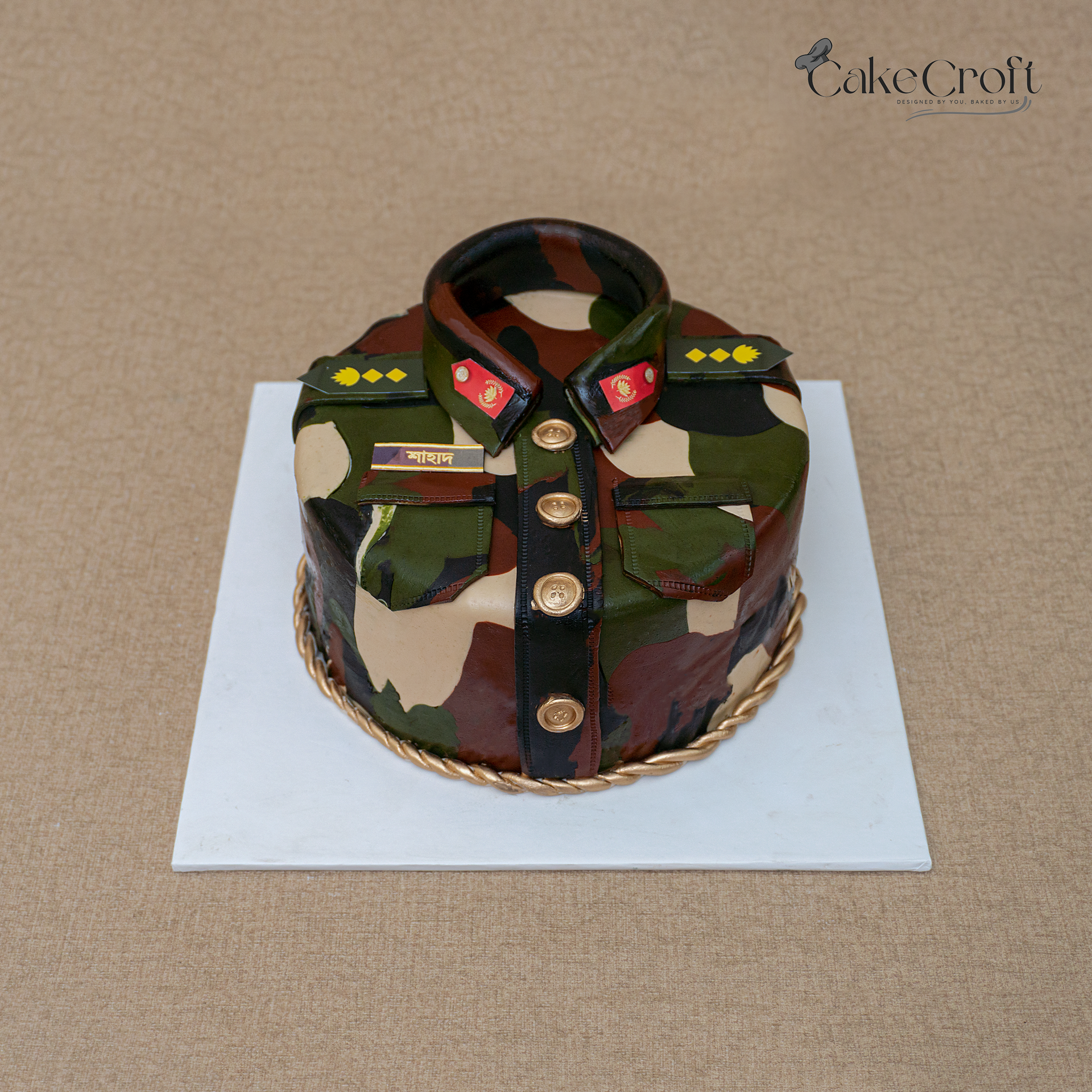 Army uniform themed cake with camouflage design, gold buttons, and military insignia.