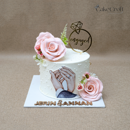 Elegant engagement cake with blush pink roses, proposal illustration, and golden ring topper in Dhaka