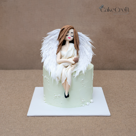 Angel themed cake with white wings and angel holding baby topper.