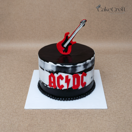 AC/DC rock band themed birthday cake with red electric guitar topper and black textured frosting.