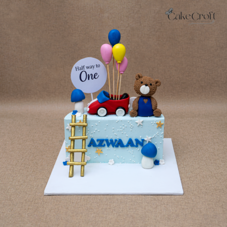 Half birthday baby cake with teddy bear, balloons, and toy car topper