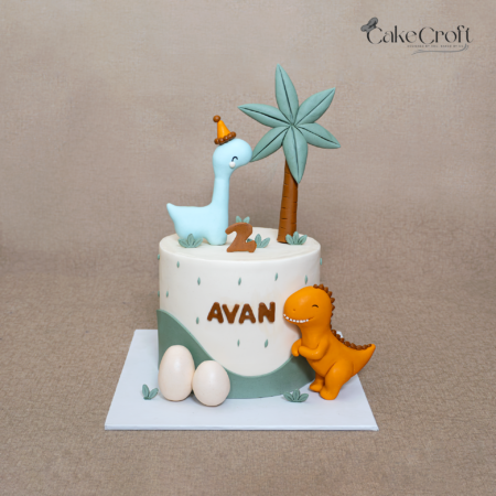 Dinosaur themed birthday cake with fondant dinos, palm tree, eggs and name Avan